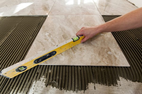 Ceramic tiles and tools for tiler. Floor tiles installation. Home improvement, renovation - ceramic tile floor adhesive, mortar, level